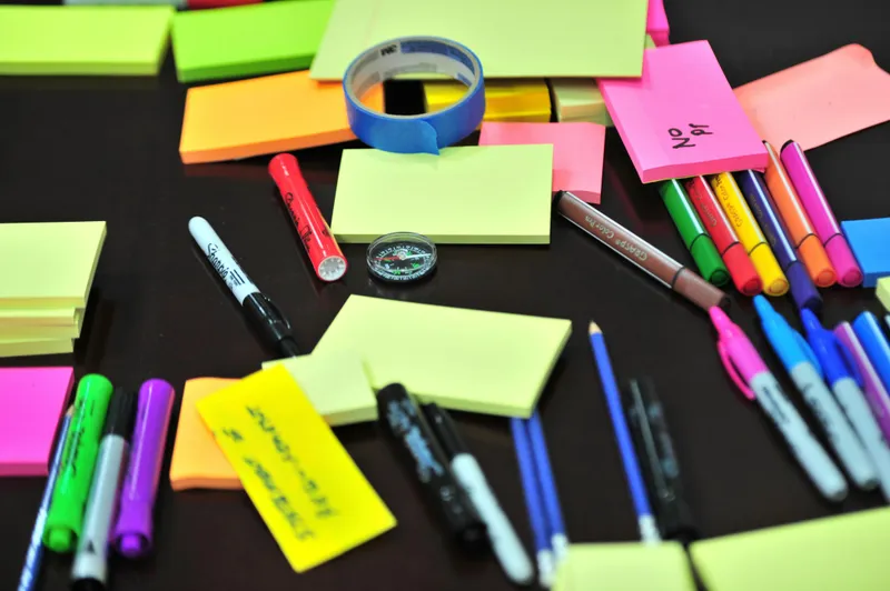 A messy table full with sticky notes and pens